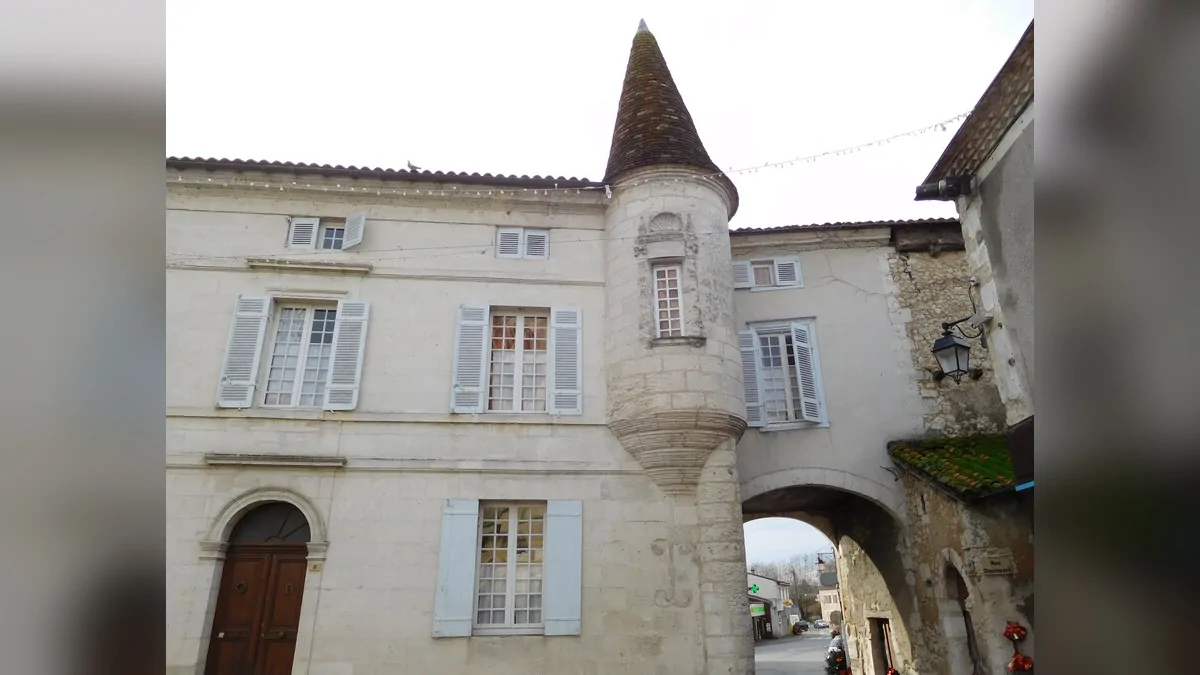 A stone house with a turret in Saint-Astier, featuring light-colored shutters.