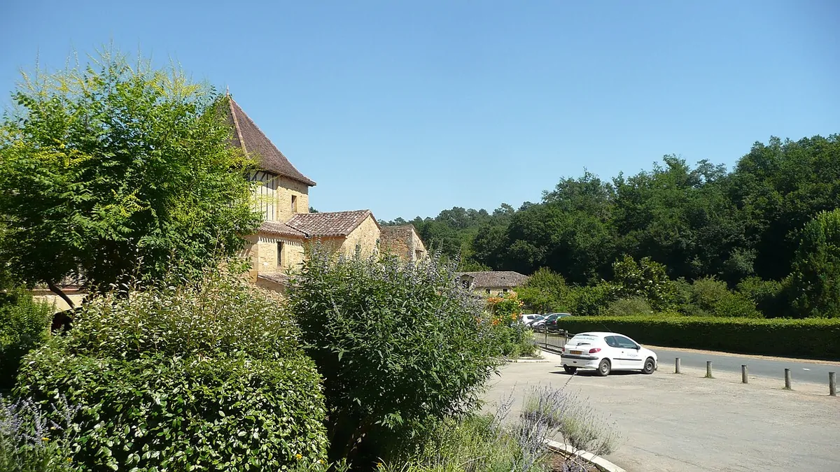 Buildings at Le Moulinal Campground in Biron, surrounded by gardens and trees.
