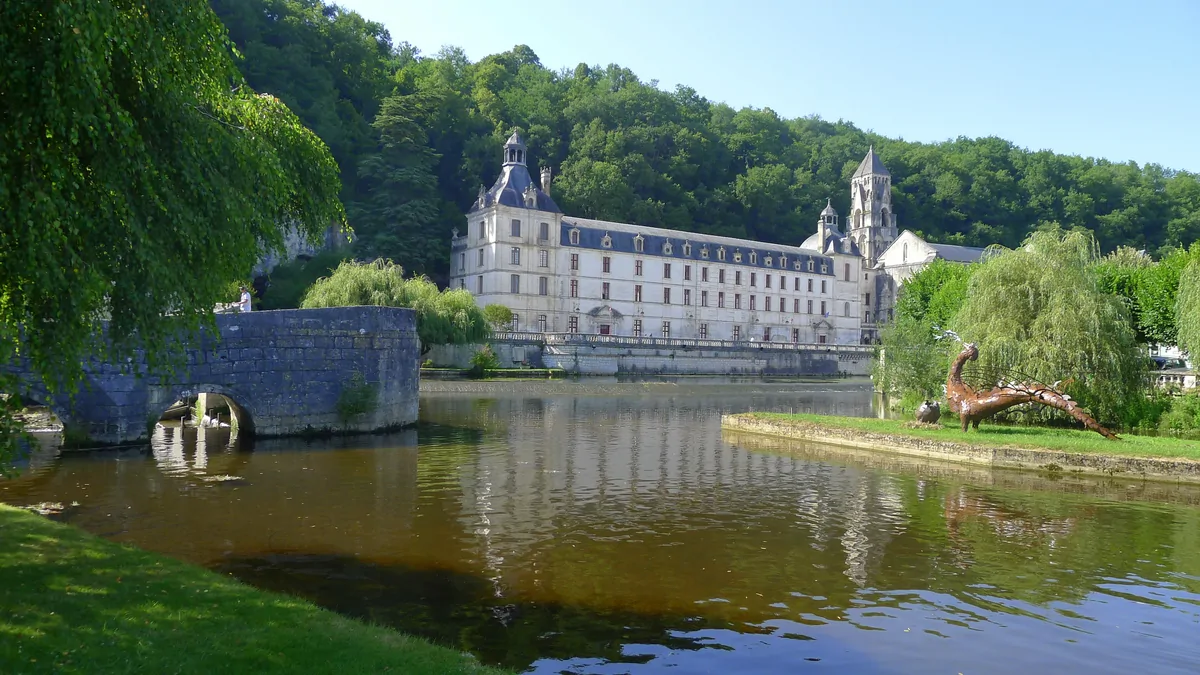 Brantôme Abbey on the banks of the Dronne River, with the stone bridge in the foreground.